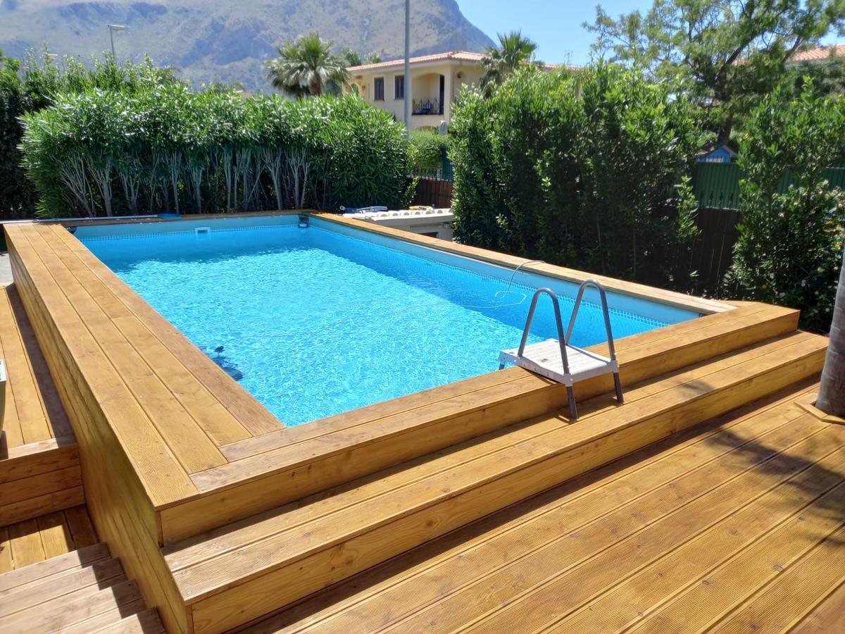 Vista d'insieme della piscina rivestita in legno con bordo continuo e scaletta